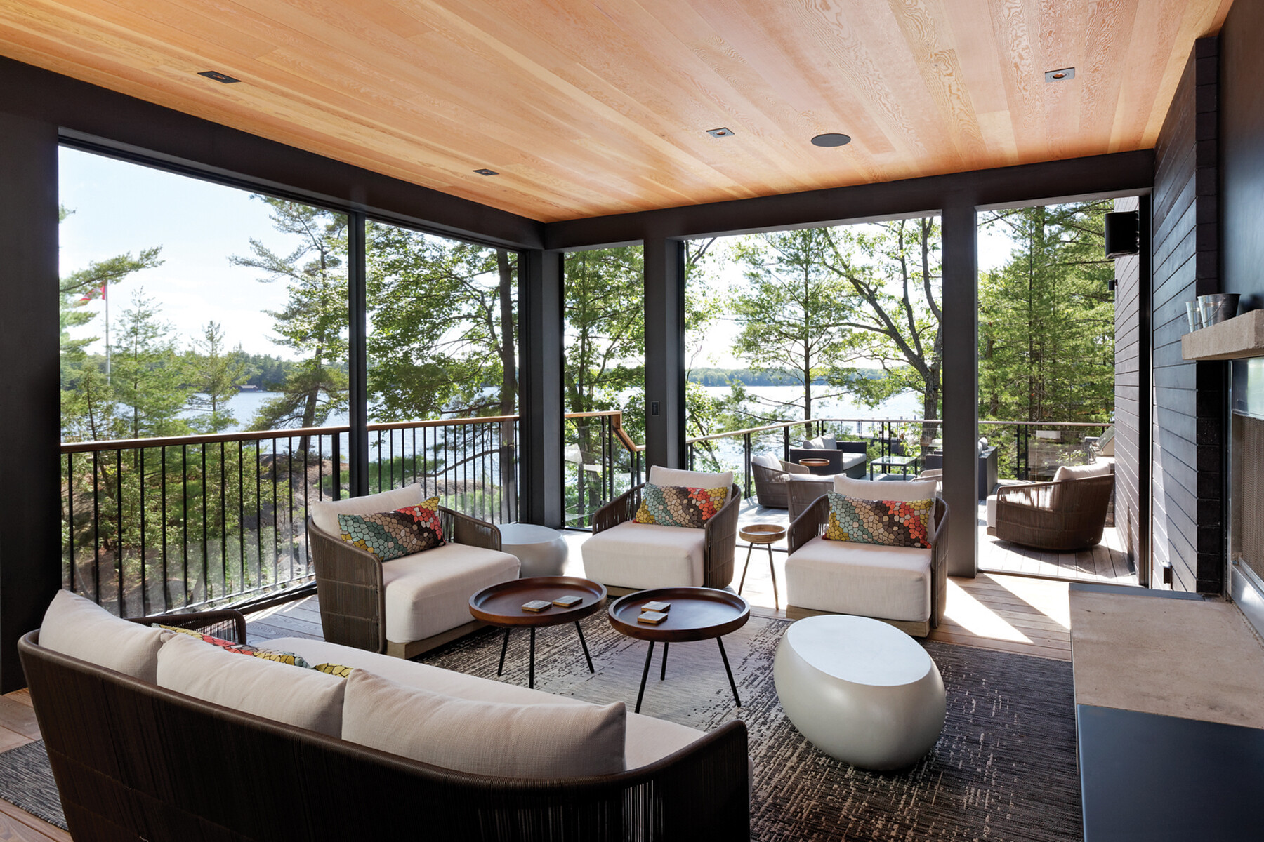 Screened porch with wood ceiling showing open connection to outdoor patio with views of trees and lake